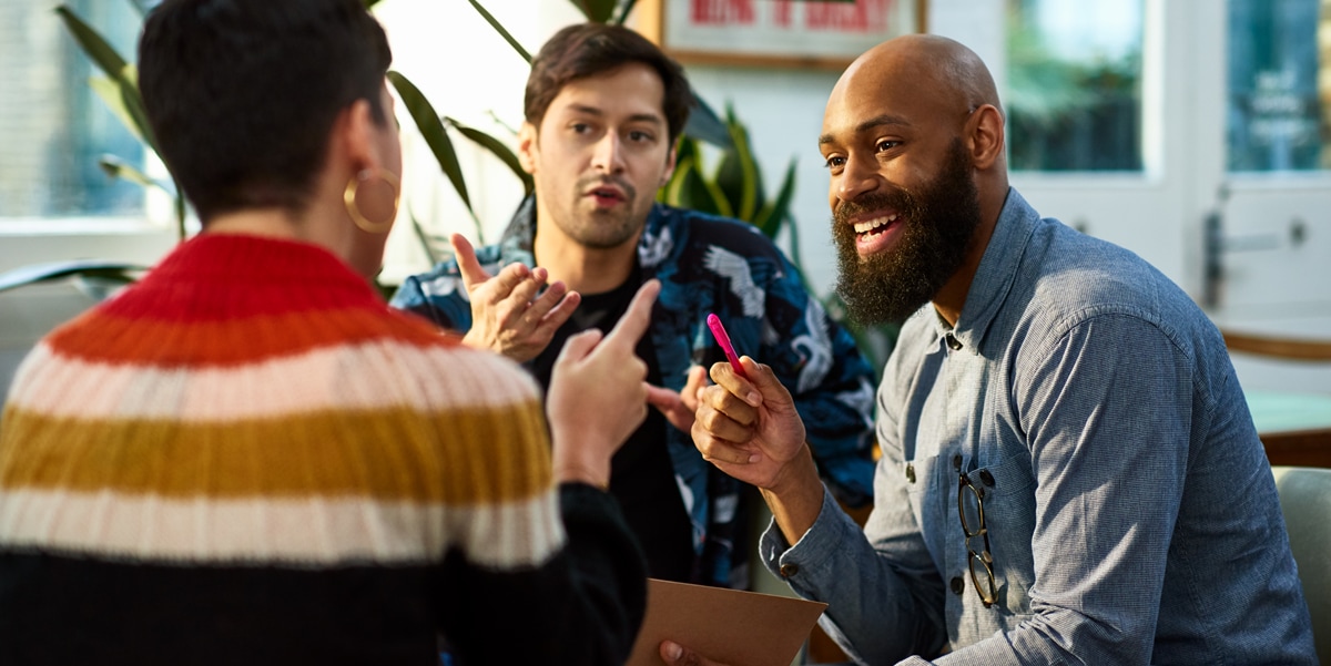 three people having a conversation in the workplace