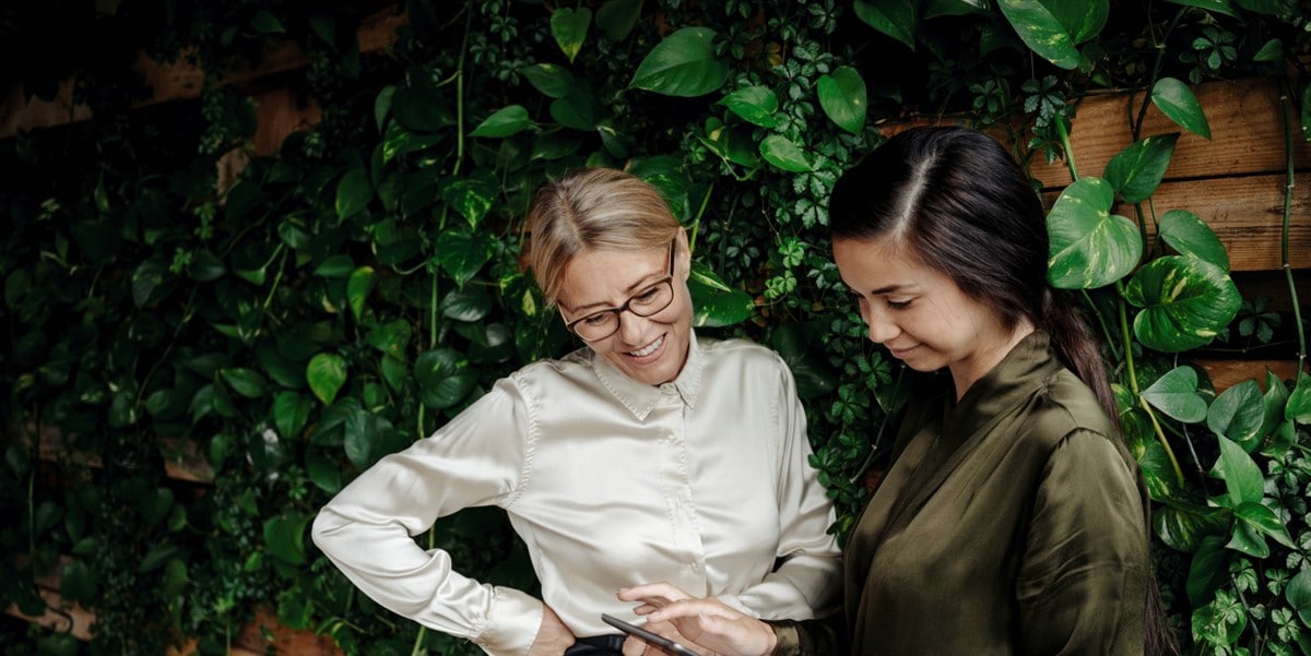 2 women standing in front of green wall