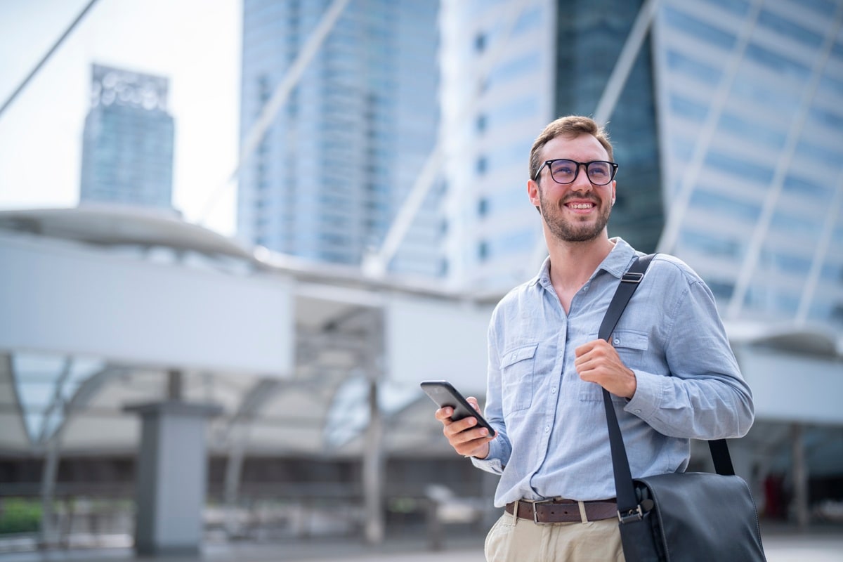 Man in city wearing glasses with bag over shoulder