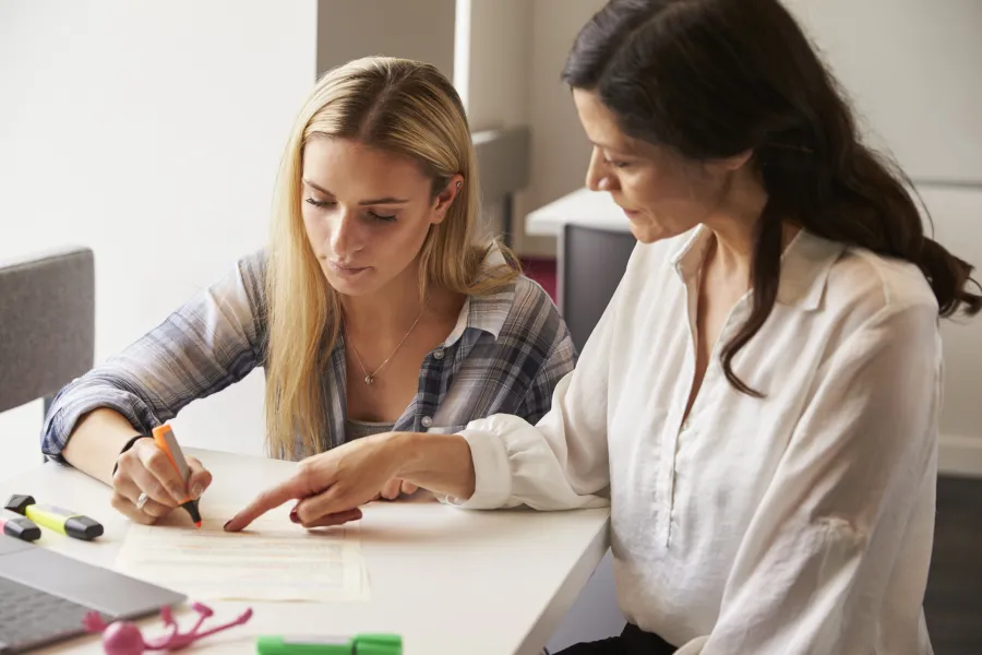 Woman writing in front of another woman